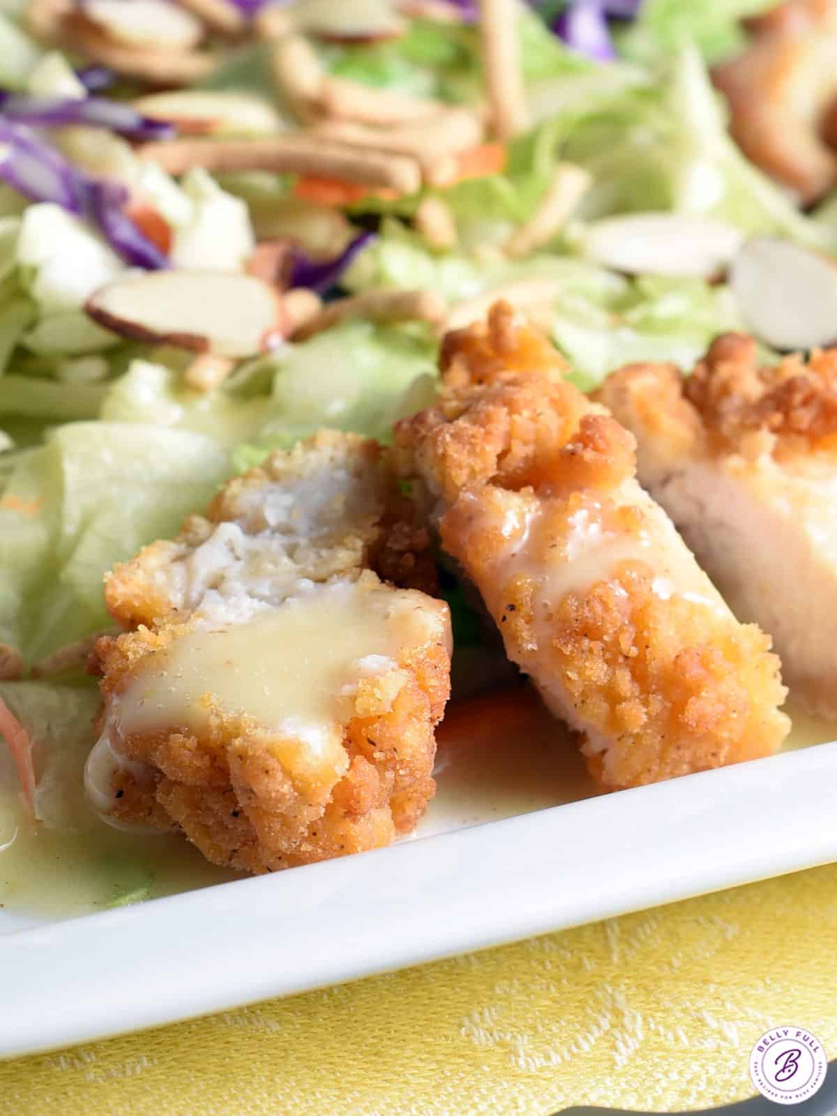 close up crispy breaded chicken pieces drizzled with with honey dressing