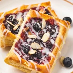 close up individual blueberry puff pastry tarts with lemon glaze