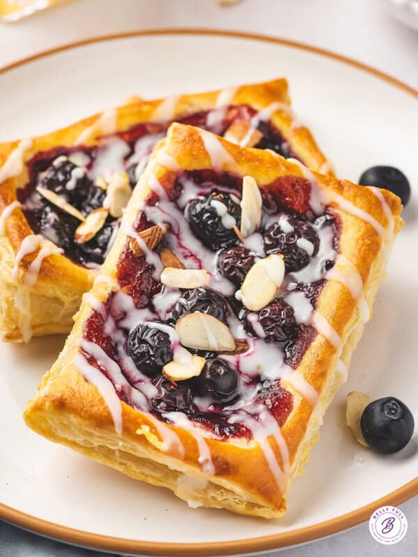 close up individual blueberry puff pastry tarts with lemon glaze