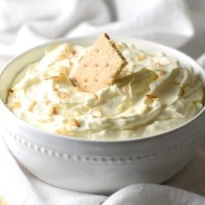 coconut cream pie dip in white bowl with graham cracker
