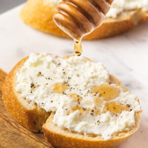 honey being drizzled over bread slice with ricotta