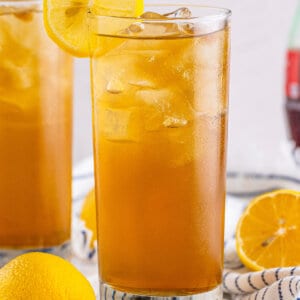 A glass of long island iced tea garnished with a lemon slice