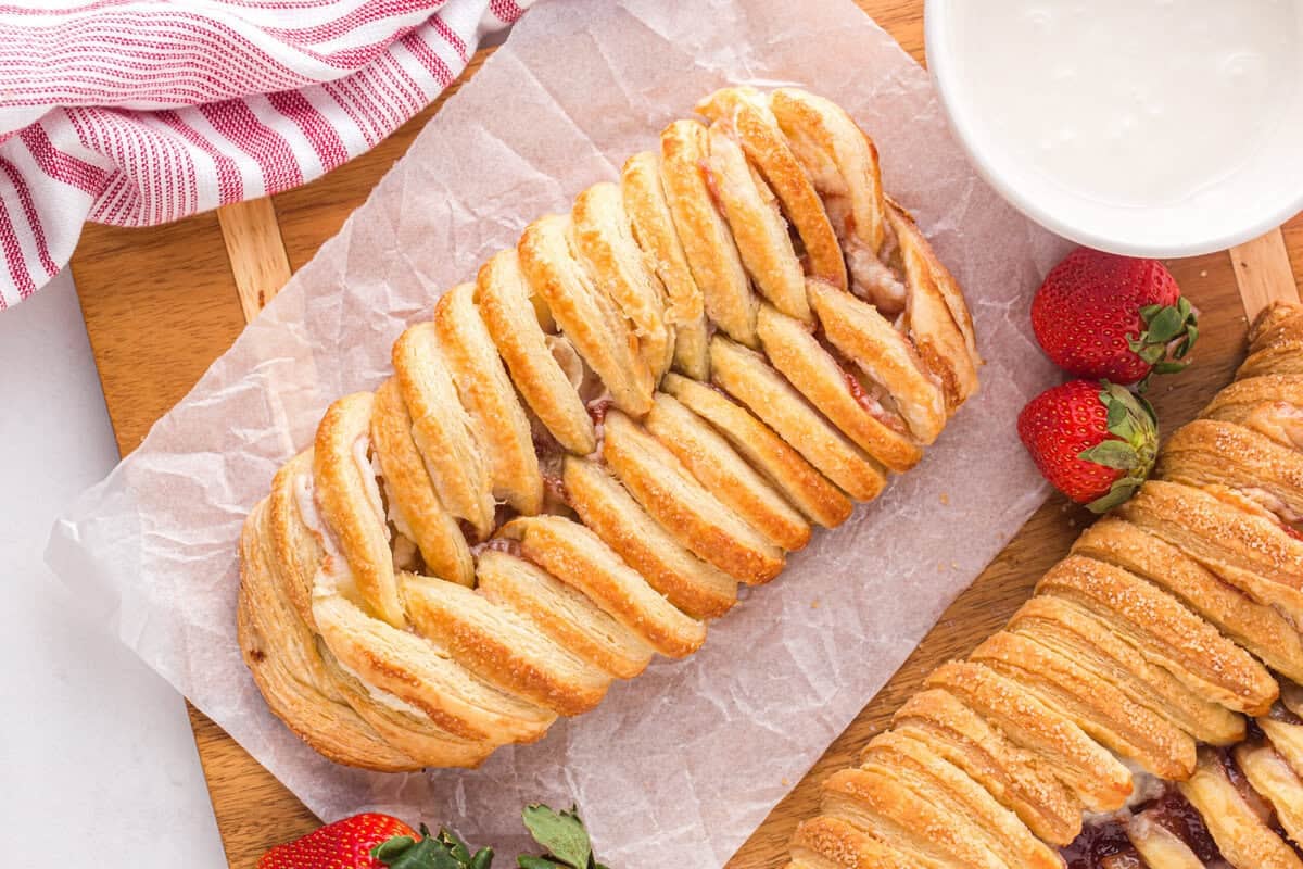 Baked Danish on a piece of parchment paper with strawberries.