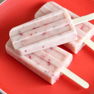 overhead 3 strawberry popsicles on red plate