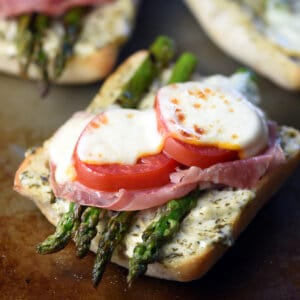 half sandwich with roasted asparagus, tomatoes, prosciutto, and melted cheese