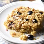 oatmeal square on plate with blueberries and maple syrup