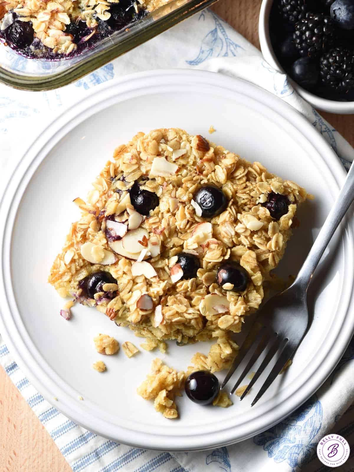 slice of baked oatmeal with blueberries and almonds on plate with fork