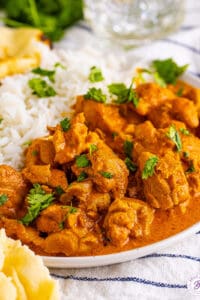 Angled view of a plate of butter chicken with rice