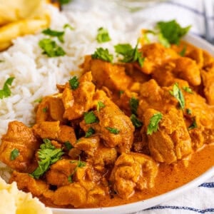 Angled view of a plate of butter chicken with rice