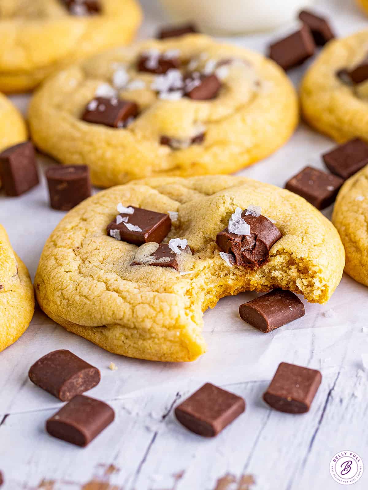 Angled view of chocolate chunk cookies on the counter, one with a bite missing