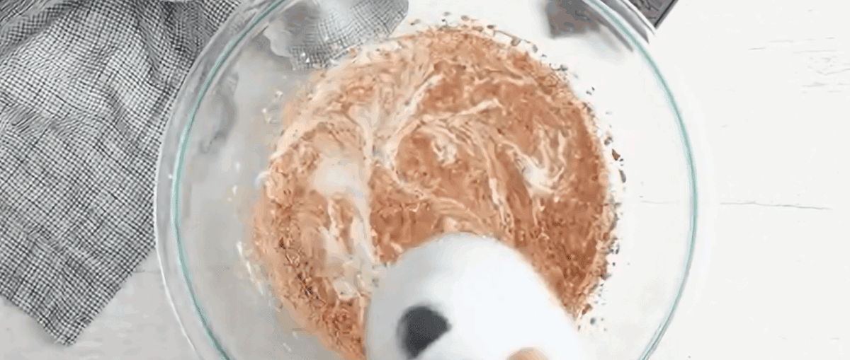 Blending heavy cream and dry ingredients in a glass mixing bowl.
