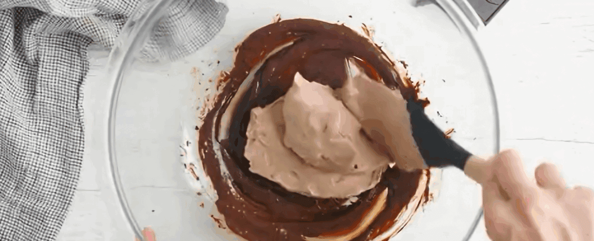Adding the whipped cream to the melted chocolate.