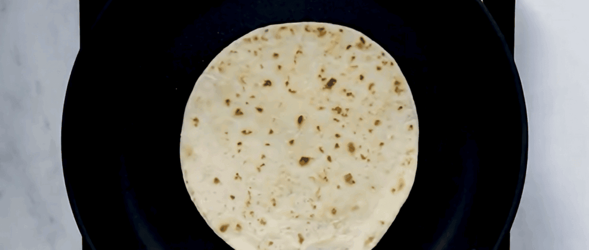 Heating tortillas in a skillet.
