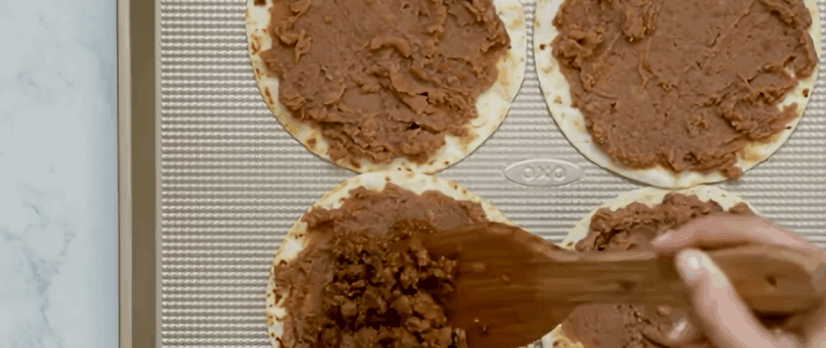 Layering beans and meat on tortillas.
