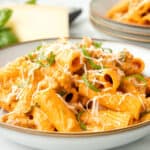 creamy sausage pasta on plate with parmesan and basil