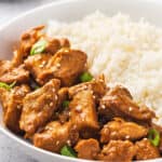 Angled view of a bowl of orange chicken with rice