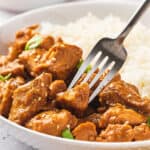 A fork stabbing a piece of crockpot orange chicken