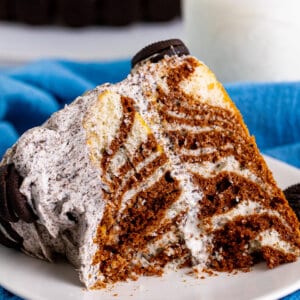 A slice of zebra cake on a plate with a bite missing