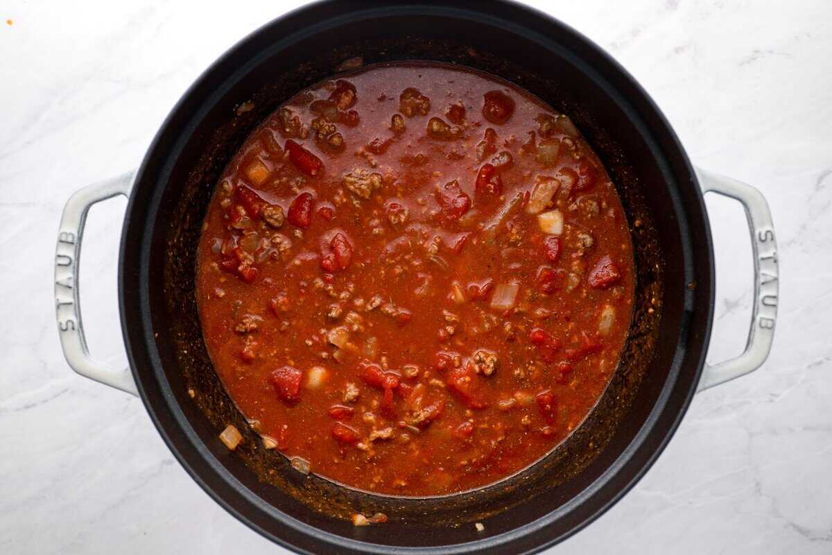 Adding tomato paste, marinara sauce, diced tomatoes, and seasonings to the pot.