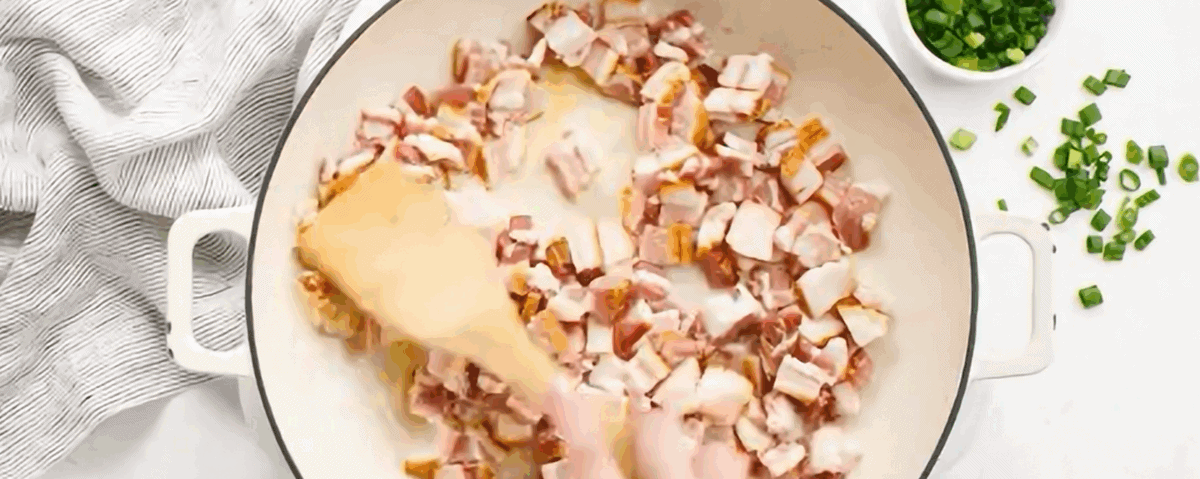 Cooking bacon in a white skillet.