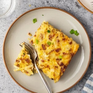 Slice of Amish breakfast casserole on a plate with a fork.