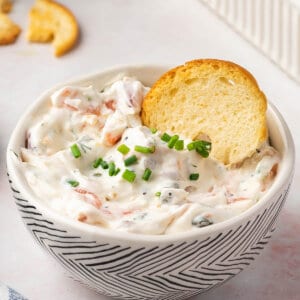 smoked salmon dip in bowl with chives and a cracker