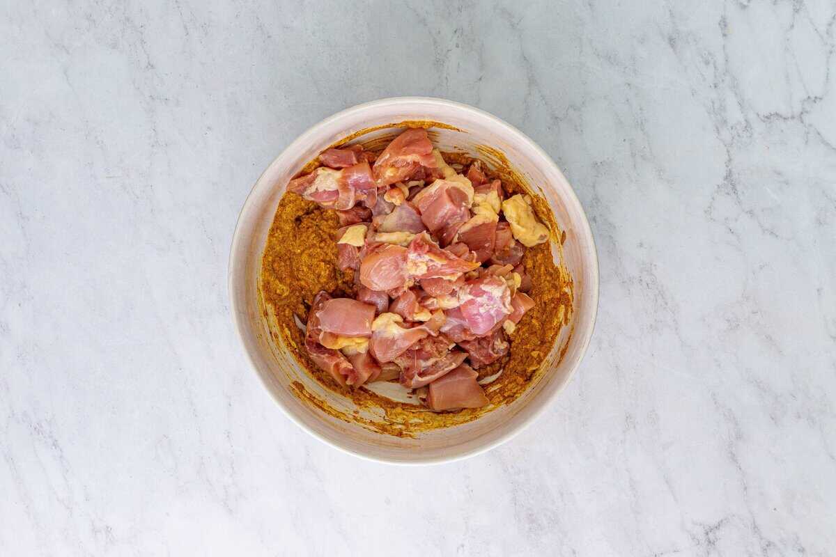 Chicken in the marinade in a white bowl.