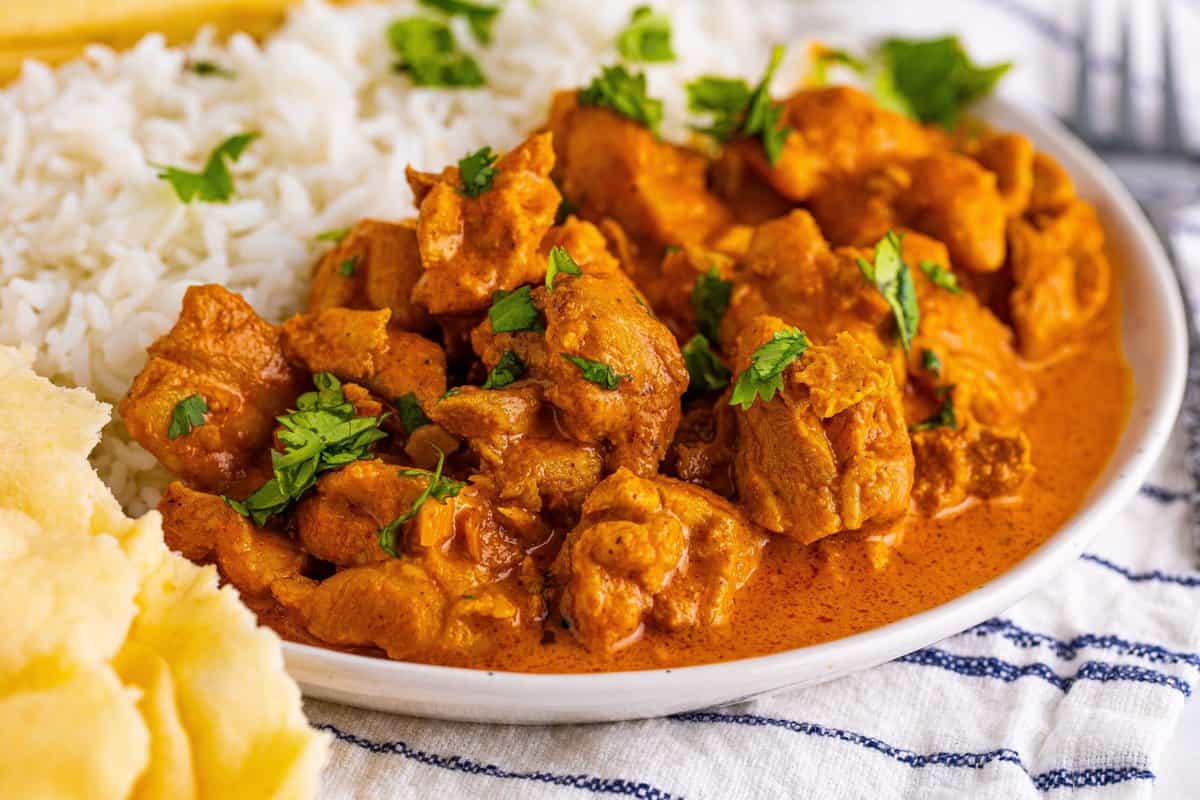 Butter chicken on a plate with rice.