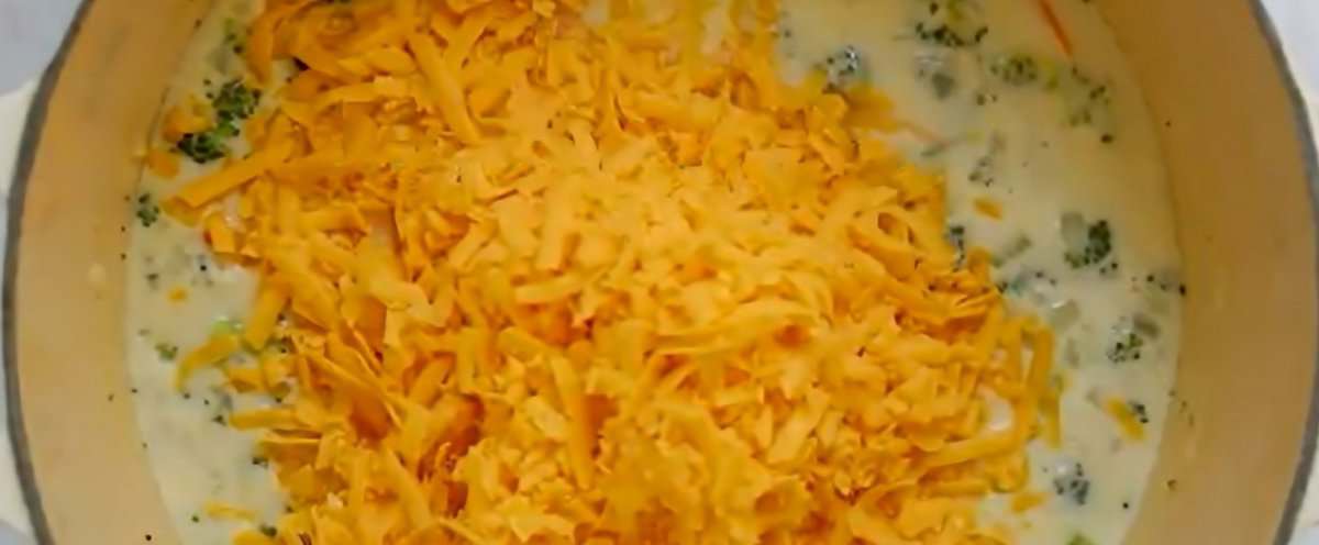 Cheddar cheese added to the pot of soup.