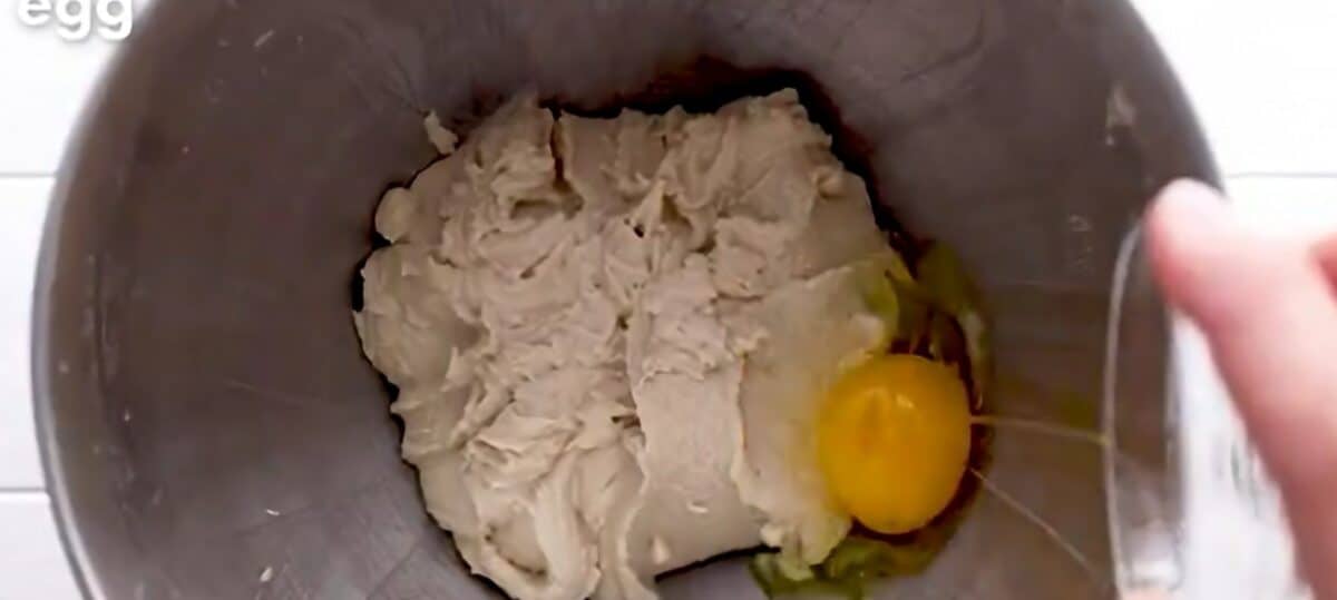 Adding eggs to the batter one at a time.