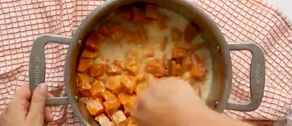 Mashing the sweet potato and milk/butter with a potato masher.