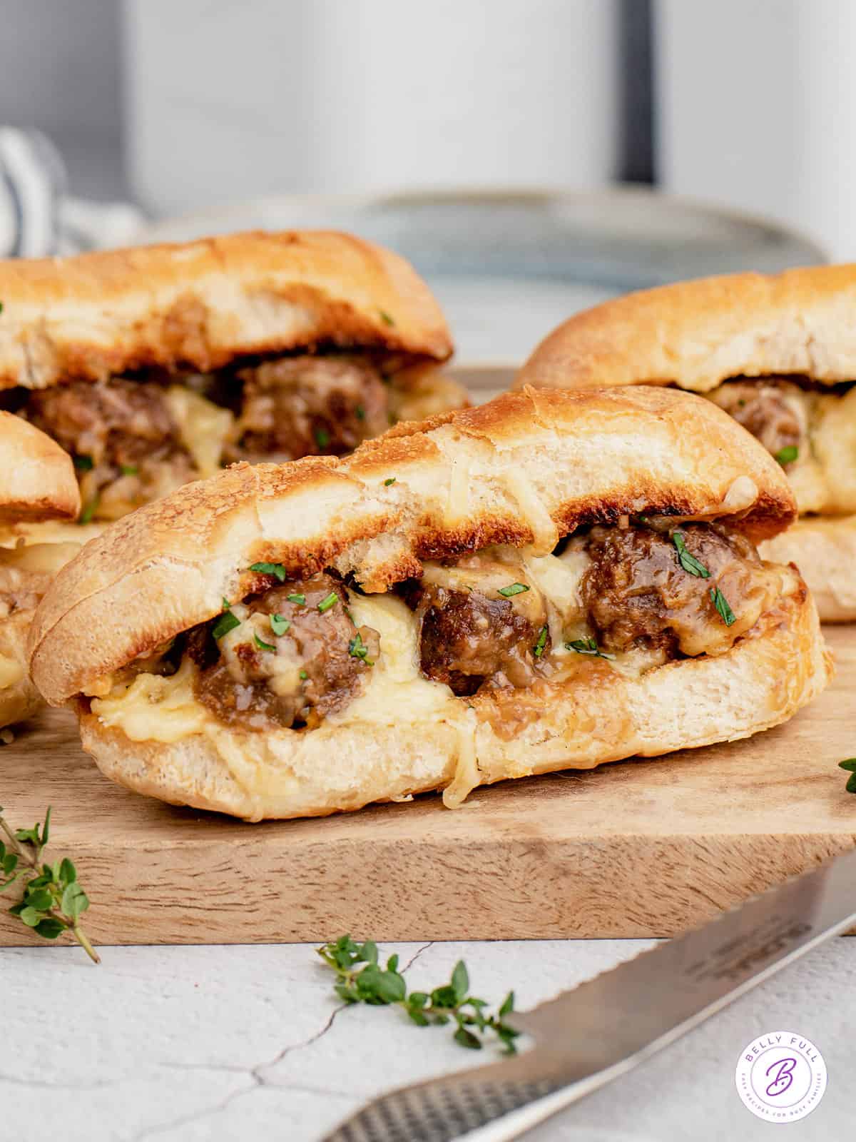 Three salisbury steak meatball subs on a cutting board