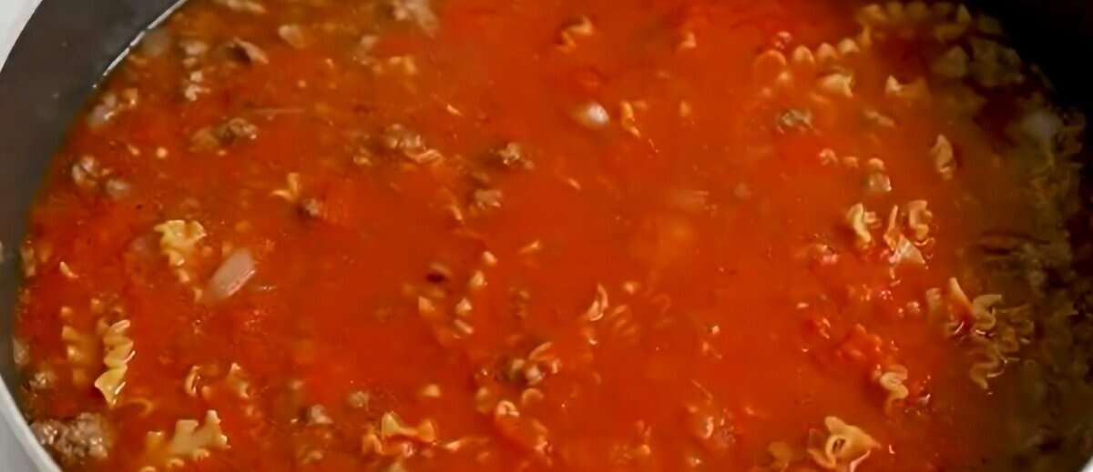 Marinara sauce, beef broth, and pasta added to the skillet.