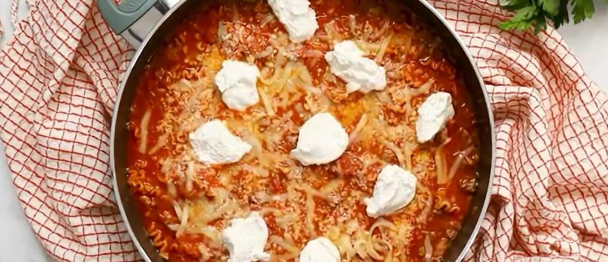 Adding dollops of ricotta cheese to the skillet lasagna.