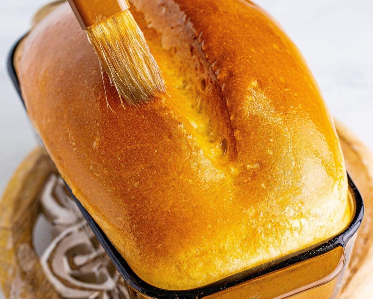 Brushing melted butter over the baked bread.