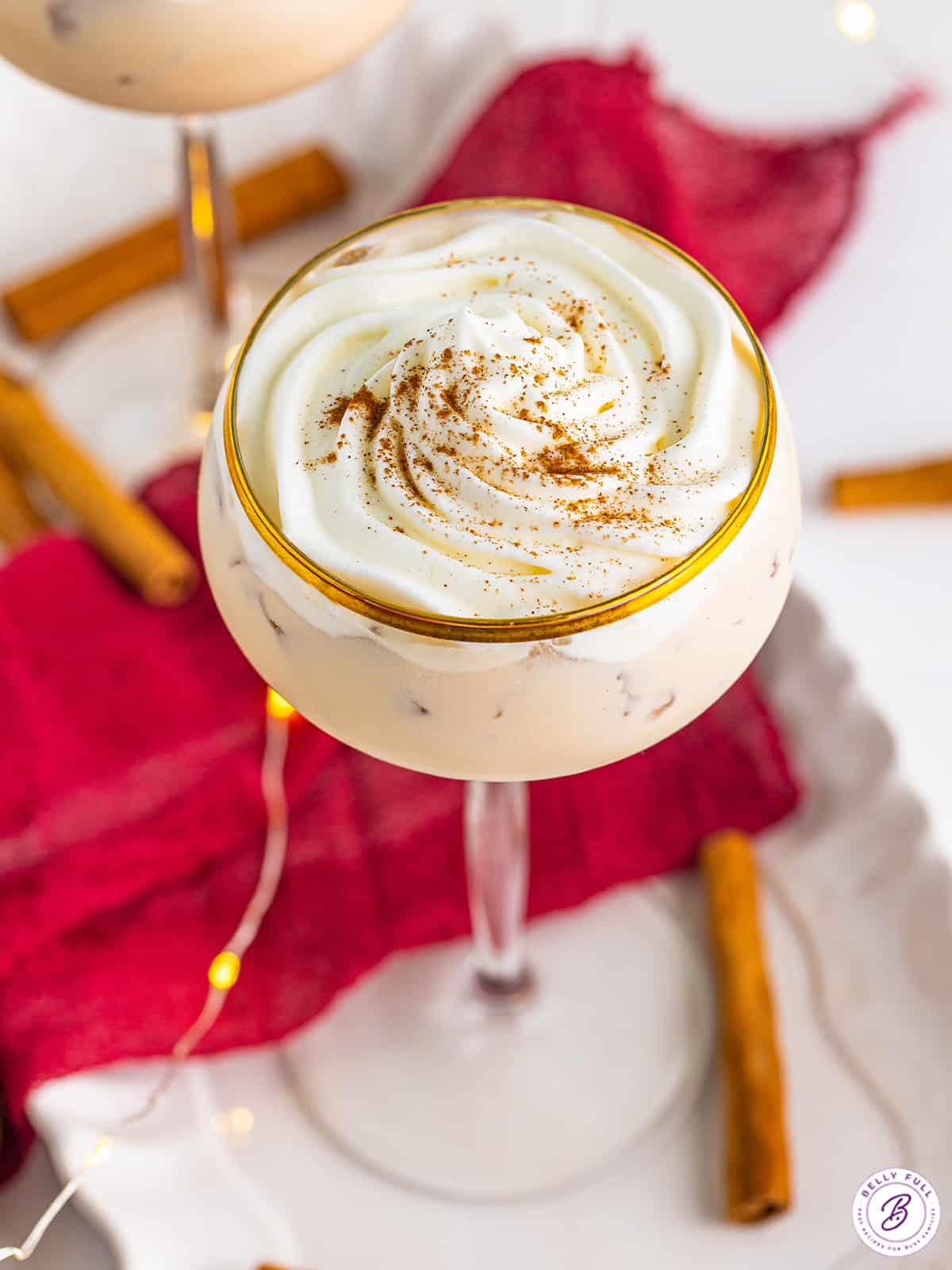 Angled overhead view of a cinnamon roll cocktail topped with whipped cream