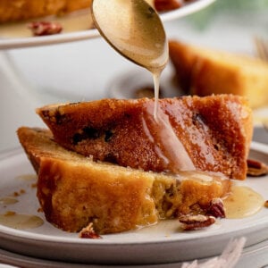 A spoonful of rum syrup being poured over a slice of cake