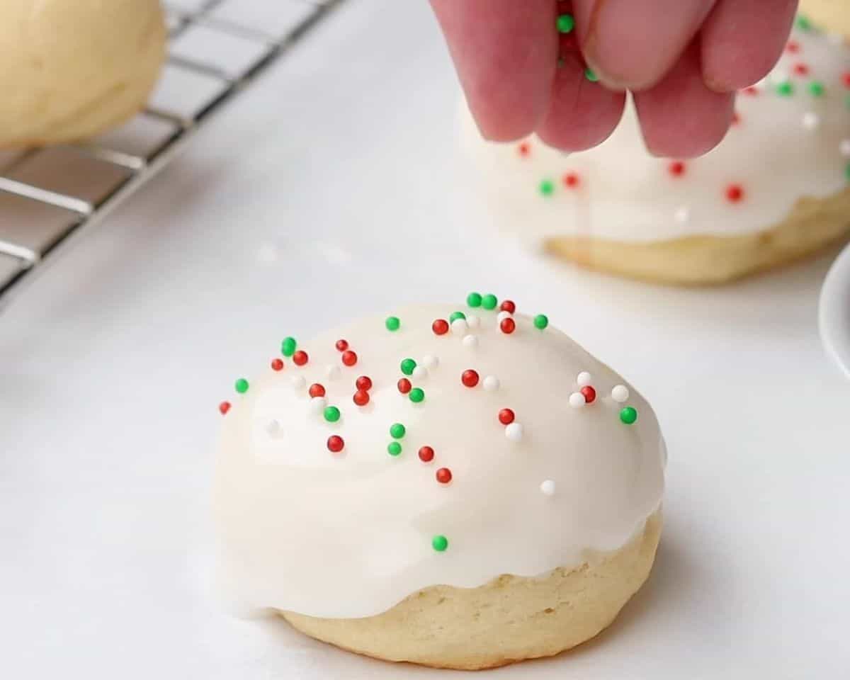 Sprinkling nonpareils on the cookies. 