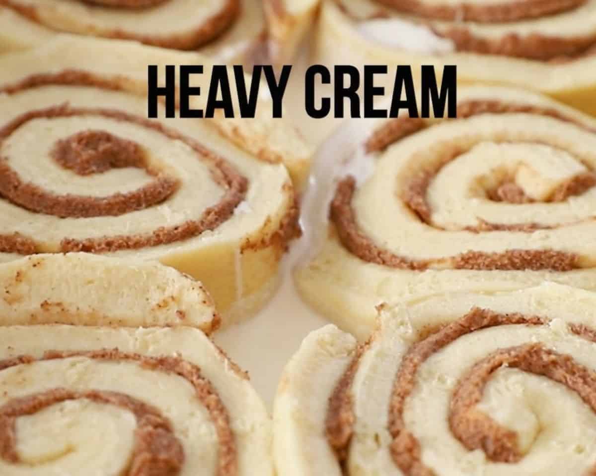 Pouring heavy cream around the cinnamon rolls. 