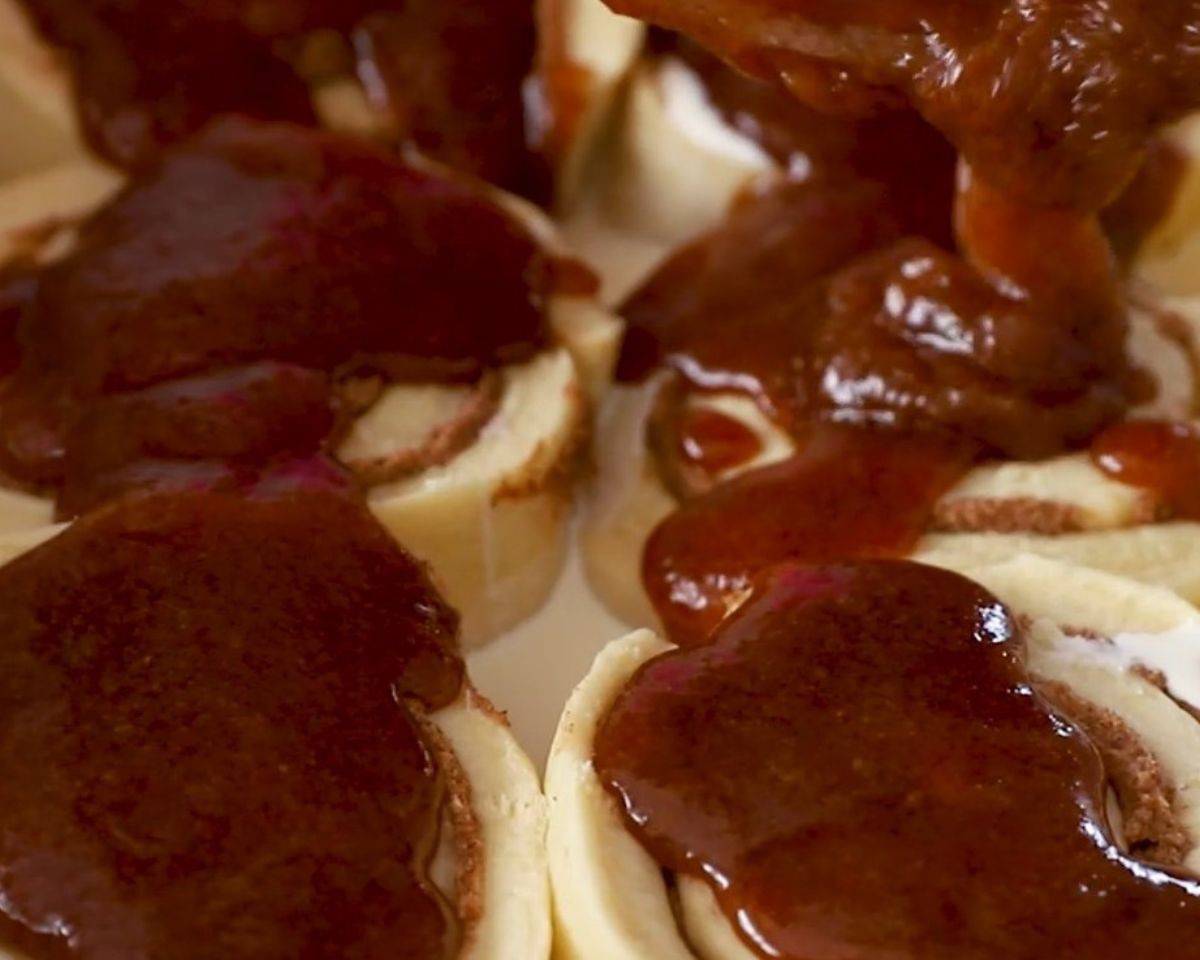 Pouring the cinnamon brown sugar mixture over the cinnamon rolls. 