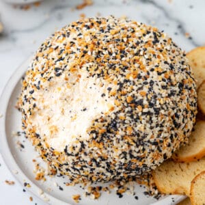 A cheese ball on a plate with some already scooped out