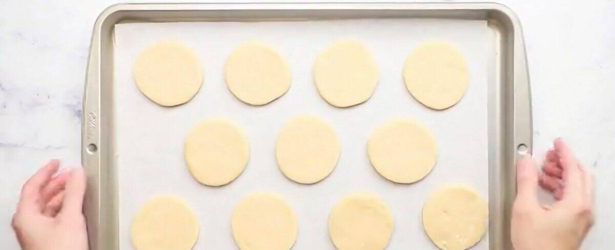 Cookie dough cut into 3" circles on a cookie sheet.