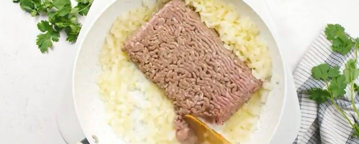 Cooking the ground beef with onions in a skillet. 