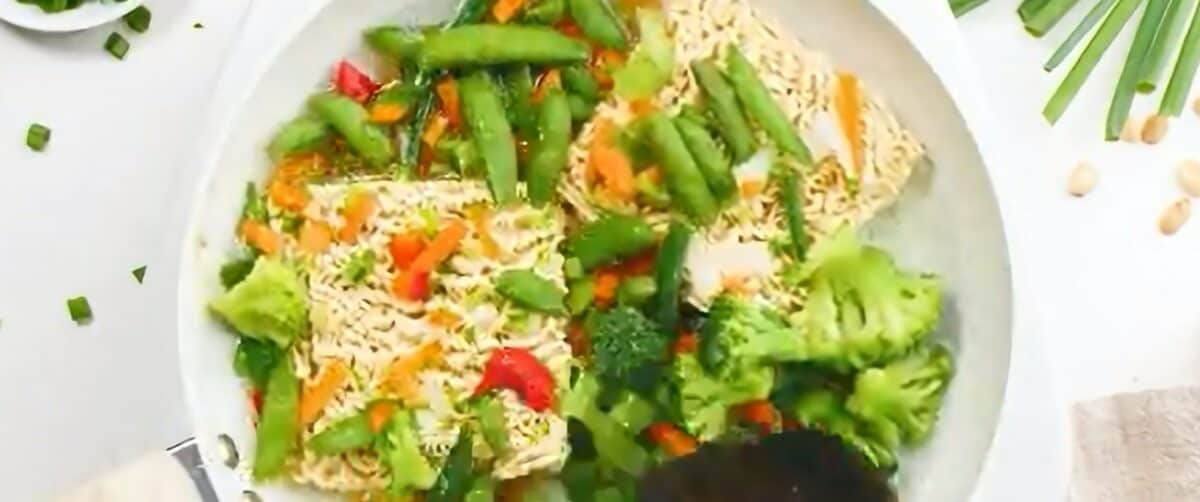 Cooking the noodles and vegetables in a skillet. 