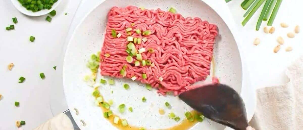 Cooking the beef and scallions in sesame oil in a skillet.