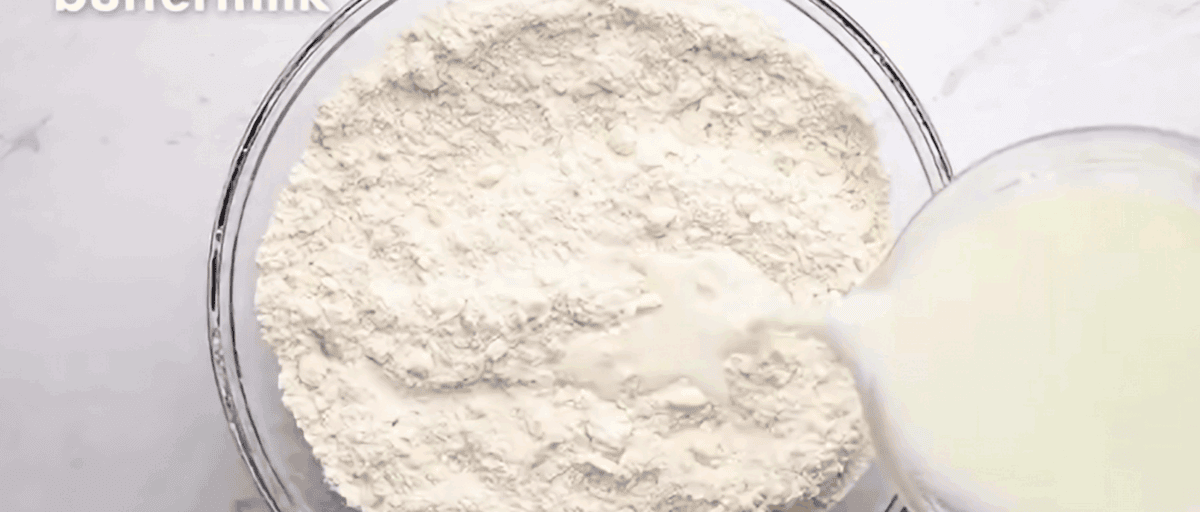 Pouring buttermilk into the ingredients to make biscuit dough. 