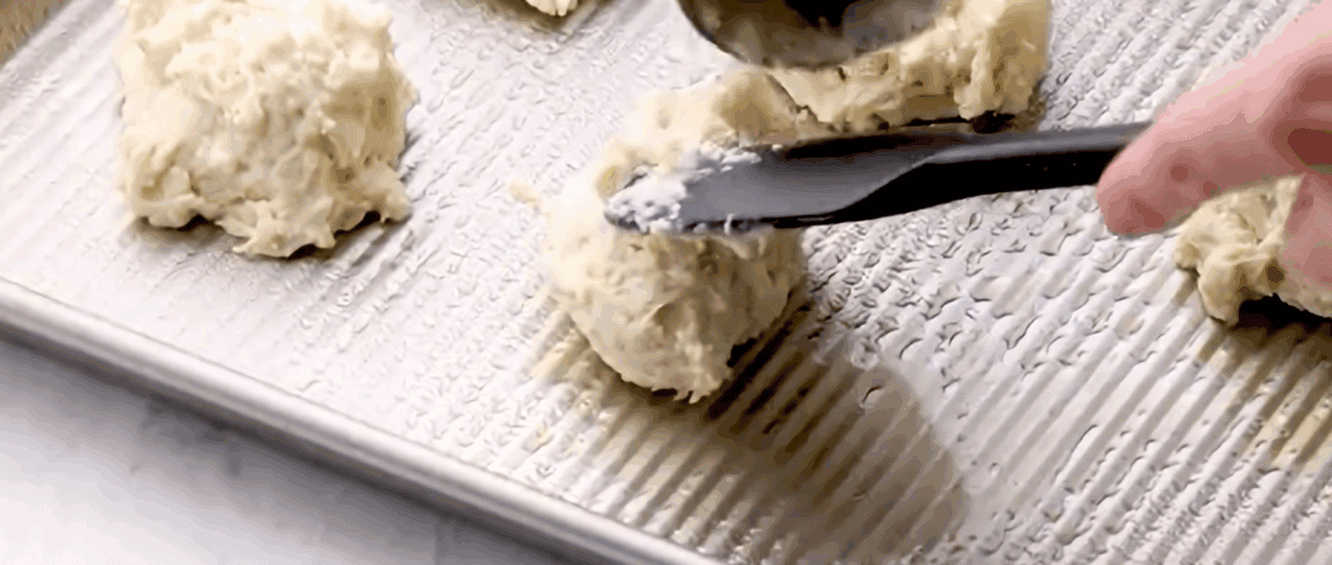 Dropping biscuit dough onto a cookie sheet. 