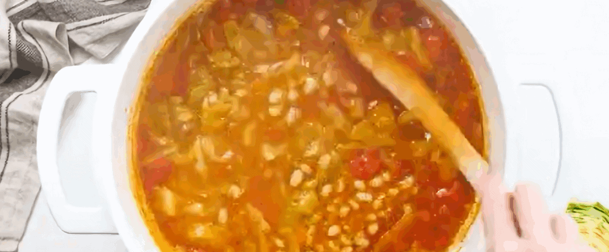 Stirring navy beans into the cabbage soup.