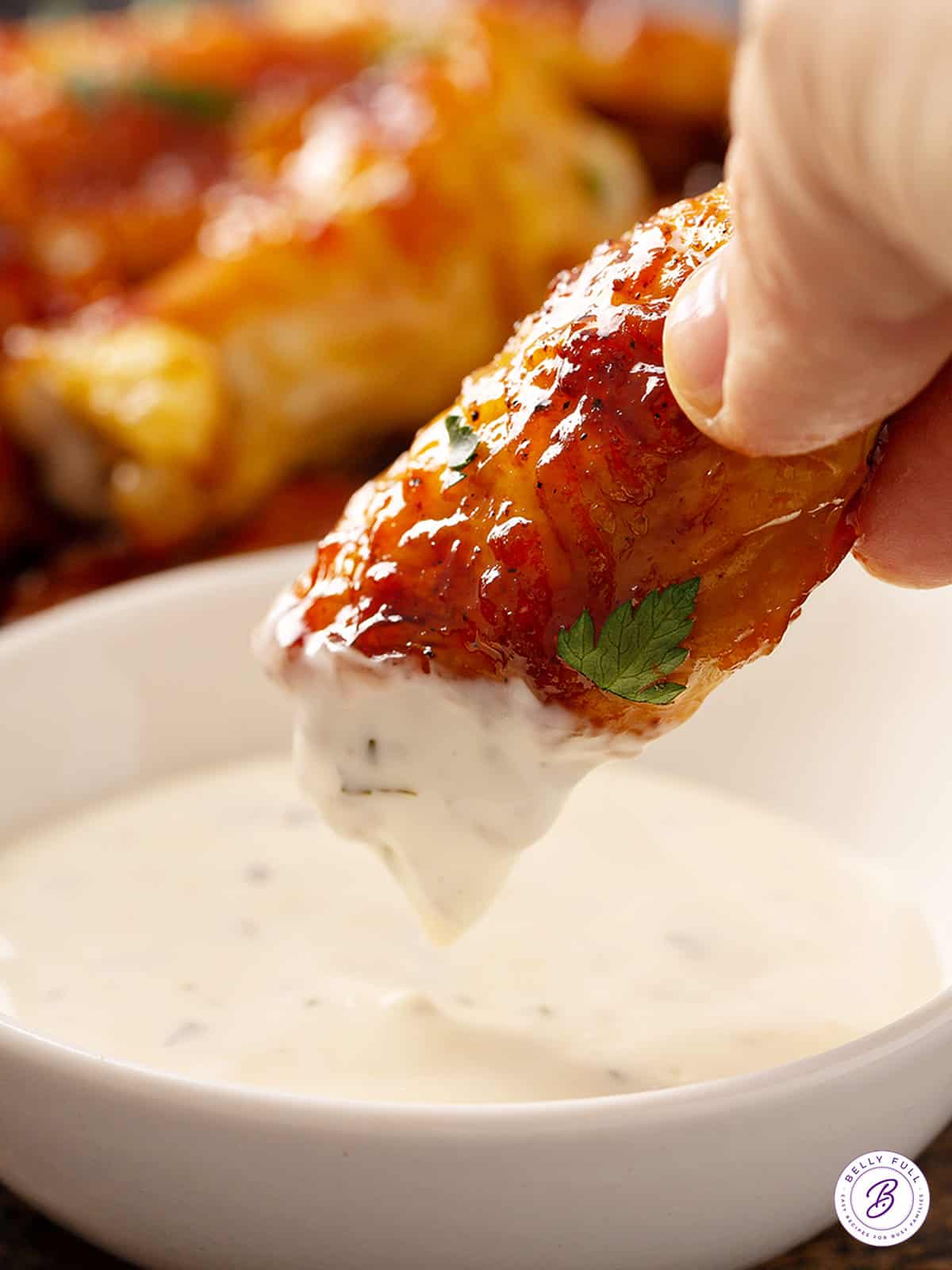 glazed chicken wing being dipped into tzatziki sauce