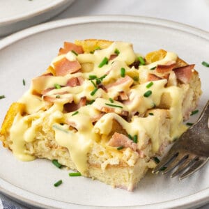 eggs benedict breakfast casserole on white plate with Hollandaise sauce